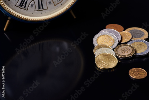clock and coins on black glass