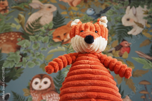 Zabawka dla dzieci rudy lis na tle kolorowej tapety