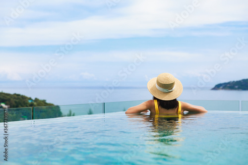 Asian travel bikini woman relax in infinity pool on phuket beach Thailand