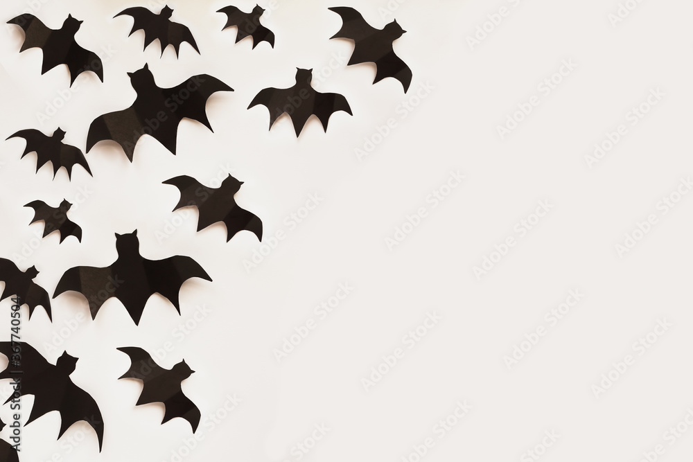 Fototapeta premium Halloween holiday decorations of many paper bats flying over an empty white background with free space for text. Top view.