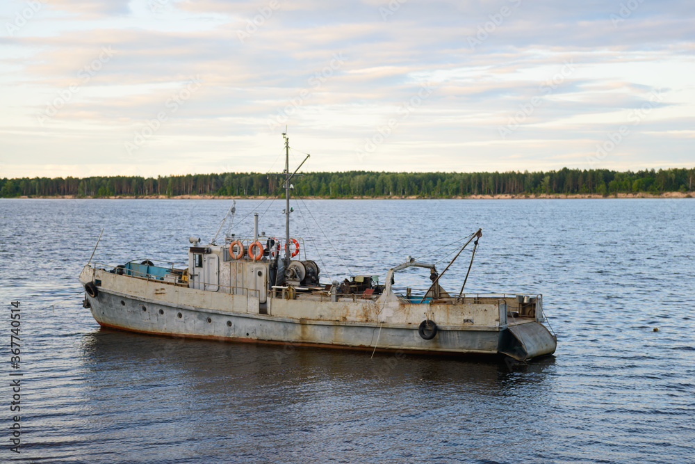 an old rusting ship stands by the waters of a wide river an old rusting ship stands by the waters of a wide river