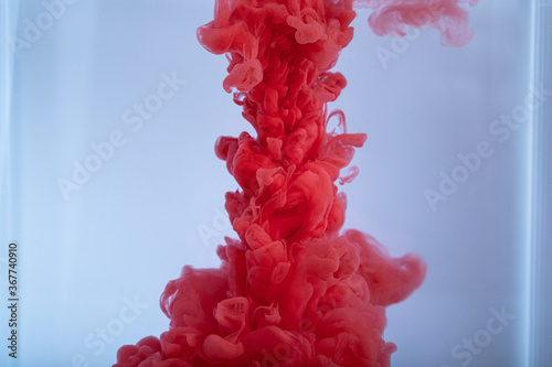 Red ink drops in water. Inky cloud swirling flowing underwater. Abstract background.