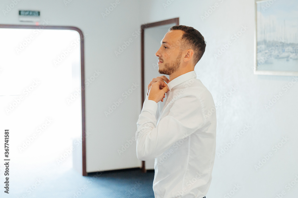 Fototapeta premium Portraits of the groom at the hotel training camp, dressed as a businessman in a black suit, tuxedo and white shirt
