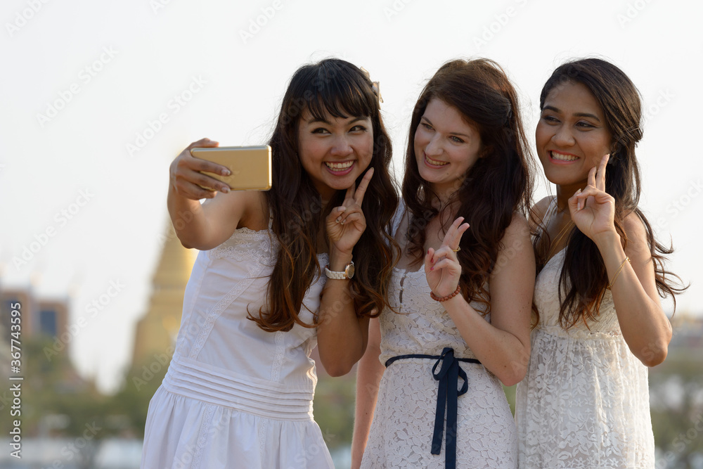 Three multi ethnic young beautiful women as friends together in the park Three multi ethnic young beautiful women as friends together in the park