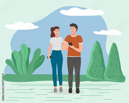 Couple walking in a park. Young guy and girl holding hands walking in summer garden, romantic walk. Man holding smartphone in hand. Romantic promenade in the open air on a date, active lifestyle