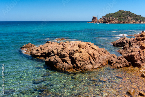 landscape, red rock above a blue bay in the beach of Su Sirboni