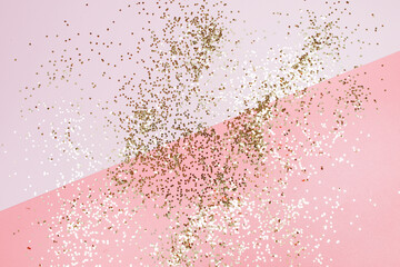 Golden stars glitter on pink background. Festive holiday pastel backdrop.