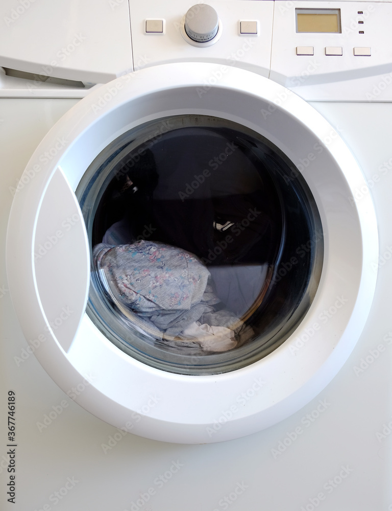 White washing machine with control buttons and dirty cloth inside