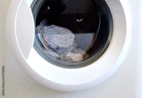 White washing machine with control buttons and dirty cloth inside © PaulPetrut