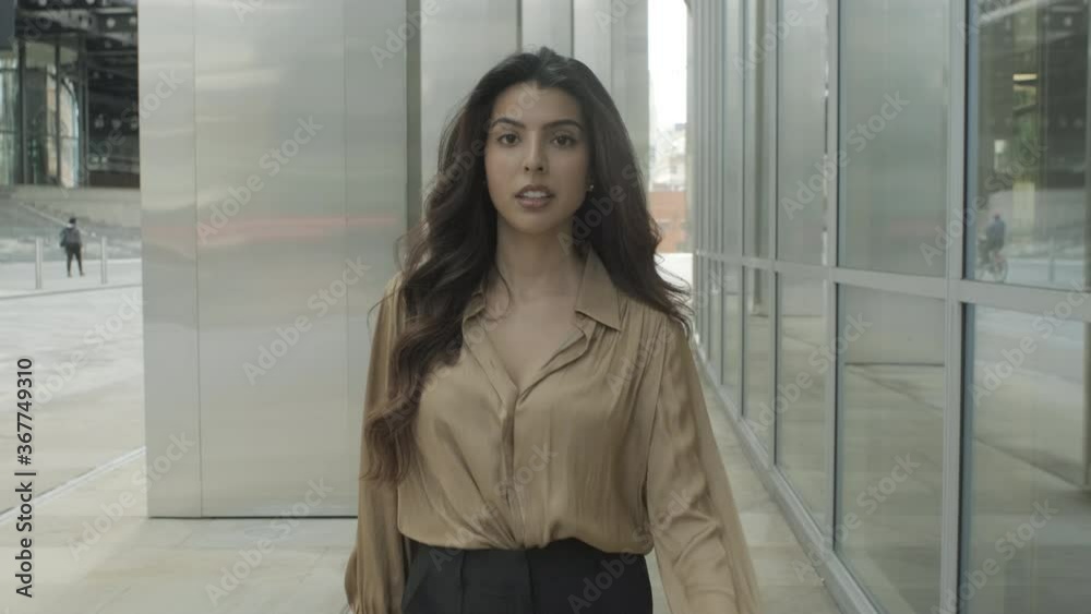 Portrait of confident young adult business woman walking in city and looking to camera, female executive moving up successful corporate career ladder Portrait of confident young adult business woman walking in city and looking to camera, female executive moving up successful corporate career ladder