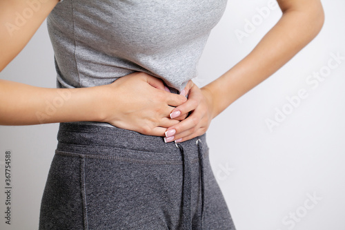 Woman feels pain in the abdomen, holding the place of pain with her hands