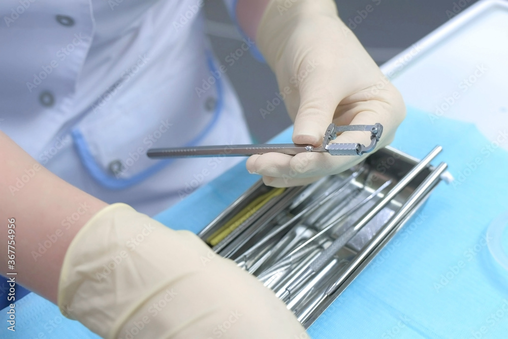 Dentist orthodontist preparing orthodontic tools for job, hands in gloves closeup. Preventive examination in dentistry. Preparing to cure in stomatology clinic. Dentist orthodontist preparing orthodontic tools for job, hands in gloves closeup. Preventive examination in dentistry. Preparing to cure in stomatology clinic.