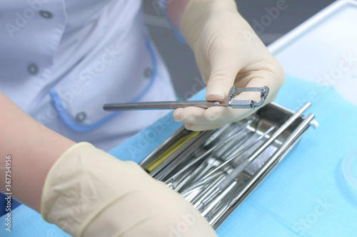 Dentist orthodontist preparing orthodontic tools for job  hands in gloves closeup. Preventive examination in dentistry. Preparing to cure in stomatology clinic.