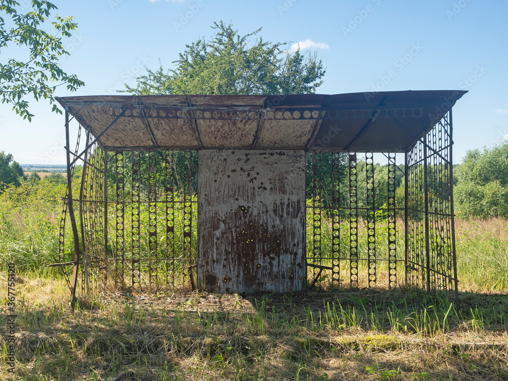 An old rusty abandoned bus stop in the countryside on a clear summer day