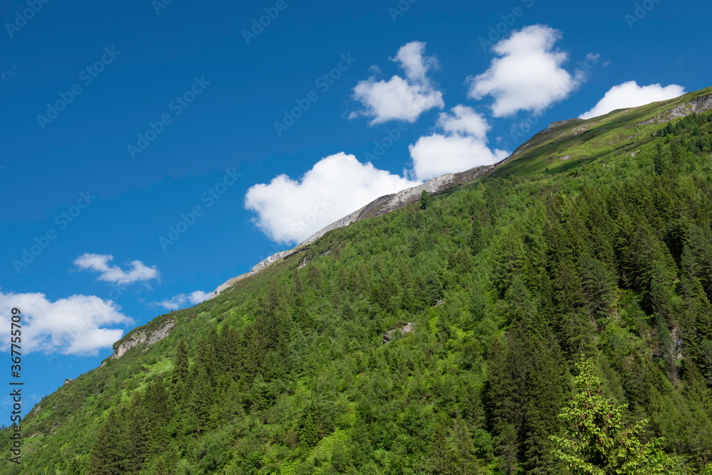 green mountain with blue sky with white clouds in two parts