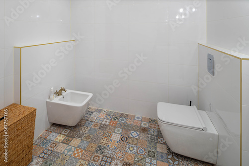 Luxury interior of modern bathroom in apartment. Clean toilet and bidet. Patterned tile.