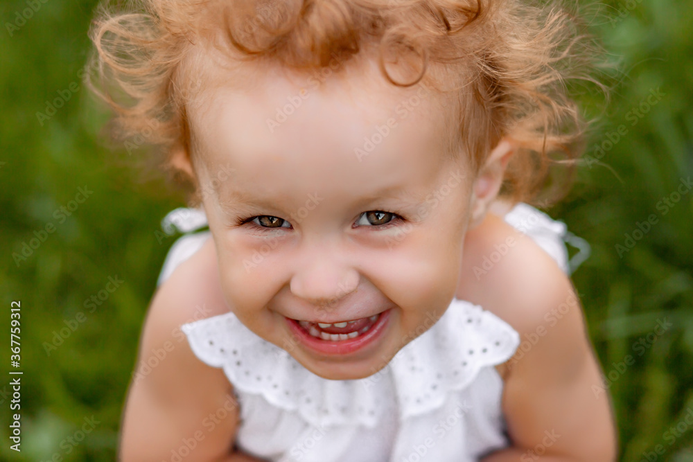 Adorable laughing little girl with long blond curly hair