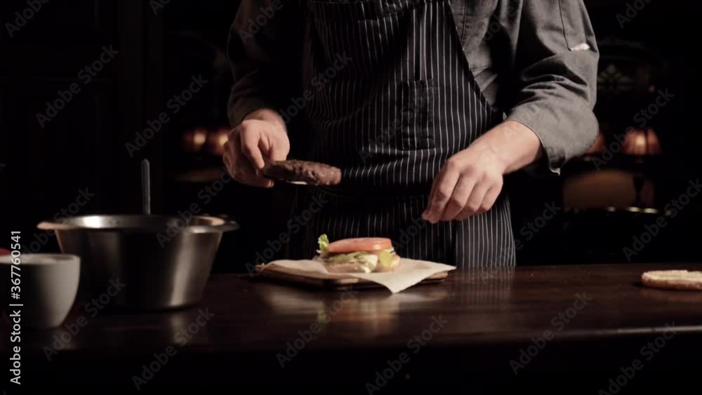Chef make a burger, puts a ring of tomato and adds a juicy cutlet on top. Cooking delicious burger. High quality 4k footage Chef make a burger, puts a ring of tomato and adds a juicy cutlet on top. Cooking delicious burger. High quality 4k footage