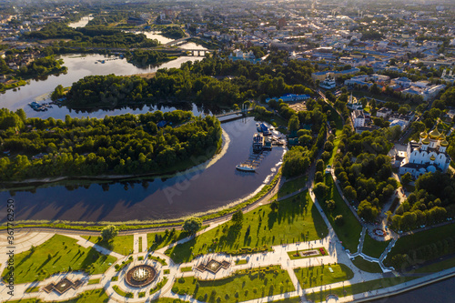 an amusement and recreation park with fountains on a peninsula next to a large river filmed from a drone