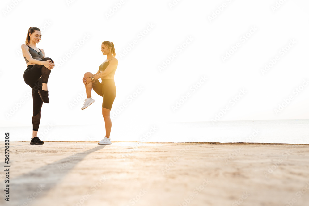 Obraz premium Women friends outdoors making stretching exercises