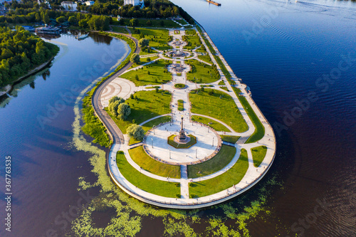 an amusement and recreation park with fountains on a peninsula next to a large river filmed from a drone