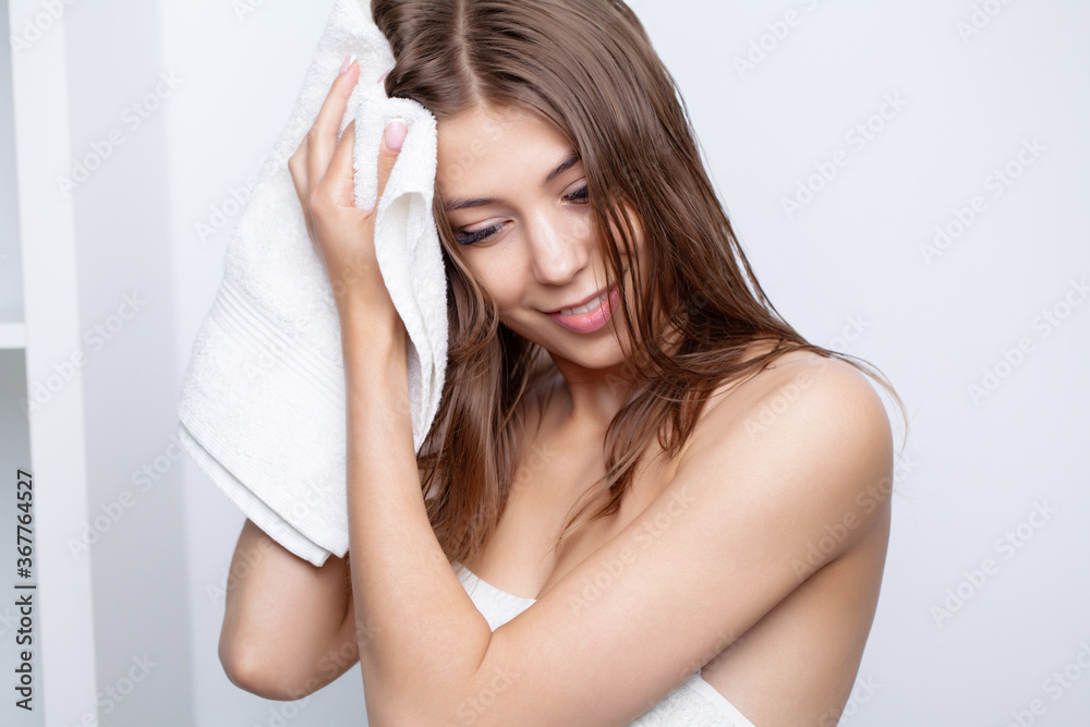 Woman with beautiful long hair wipes her head with a soft towel Woman with beautiful long hair wipes her head with a soft towel