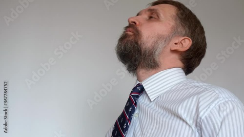 Mature man with beard wearing formal clothes takes pills and can hardly swallow them. Being healthy