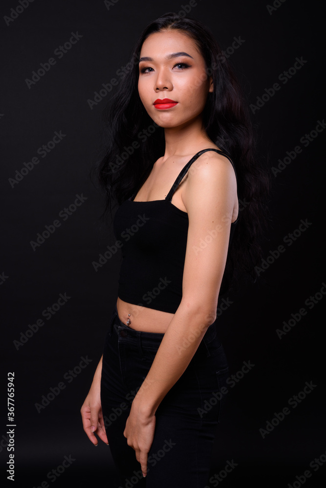 Young beautiful Asian transgender woman against black background