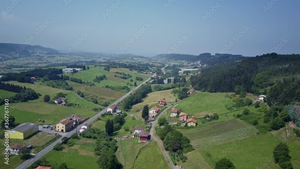 Drone orbits showing a quiet road in the town of Prendes in the middle of Asturian Natural Park with beautiful green mountains, small Asturian houses. Drone orbits showing a quiet road in the town of Prendes in the middle of Asturian Natural Park with beautiful green mountains, small Asturian houses.