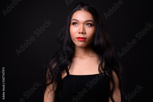 Young beautiful Asian transgender woman against black background