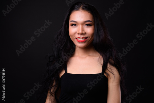 Young beautiful Asian transgender woman against black background