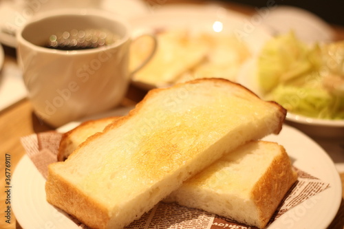 Close up of a plate of delicious hot toast bread served with a cup of hot coffee, soft focus