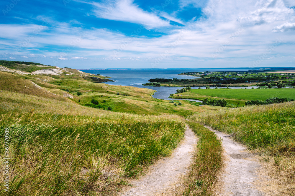 Panorama of the Russian picturesque landscape with hills and flower fields and blue sky with clouds on the background of the sea