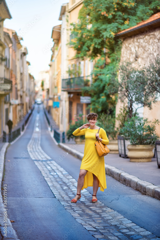 Vertical picture of old narrow stone street of Aix-en-Provence, France with tourist woman in yellow dress with yellow bag. Travel tourism destination Provence