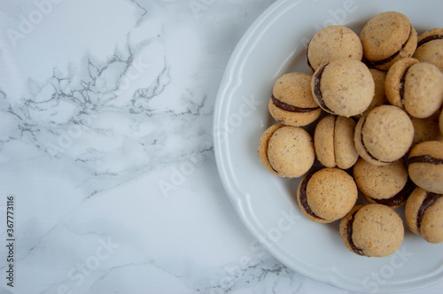 Baci di dama, lady kisses, on white plate Italian biscuits whit chocolate, marble background  photo