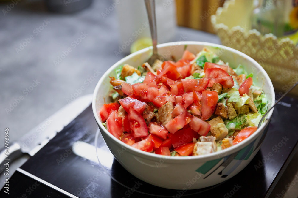 Preparation of juicy salad with chicken, iceberg lettuce and tomatoes.