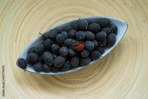 Velvet tamarind fruit ( Dialium cochinchinense) or buah keranji in a wooden bamboo plate background. photo