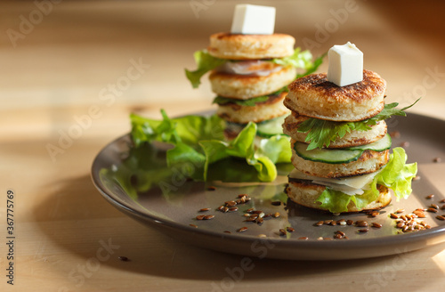 appetizer of mini pancakes, greens and soft cheese on a gray plate with flax seeds, with space