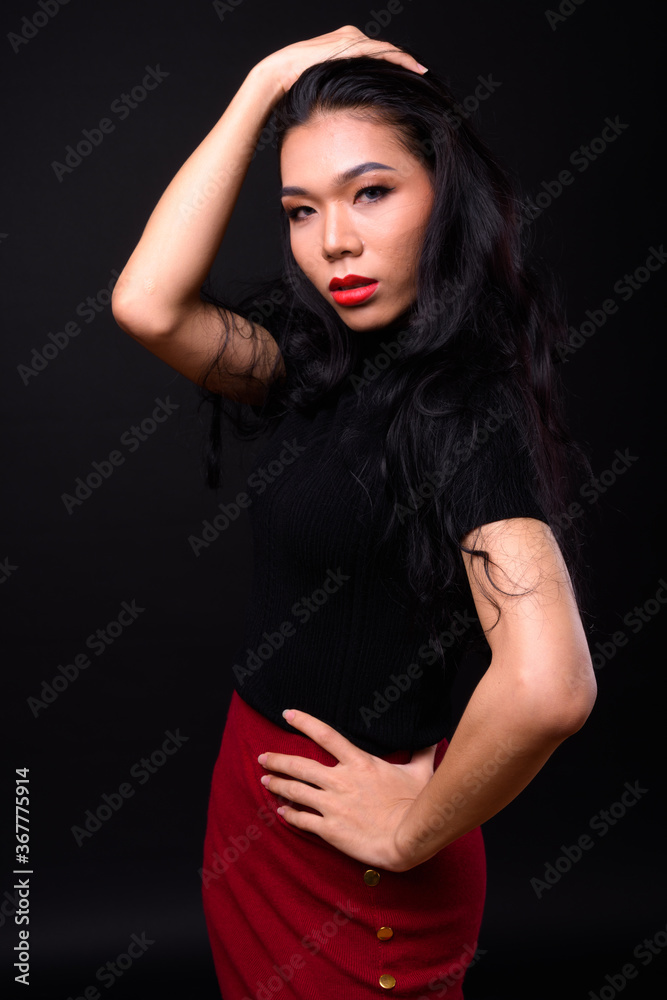 Young beautiful Asian transgender businesswoman against black background