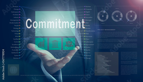 Businessman outreached hand holding a Commitment business concept on a computerised screen display.