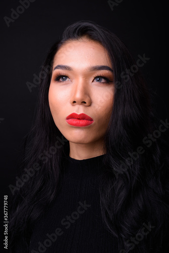 Young beautiful Asian transgender businesswoman against black background
