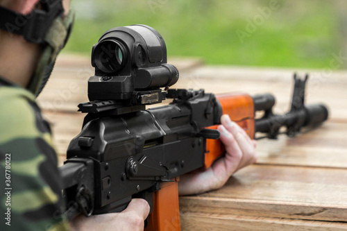 Military shooter with his precising assault rifle aiming and shooting target in the range