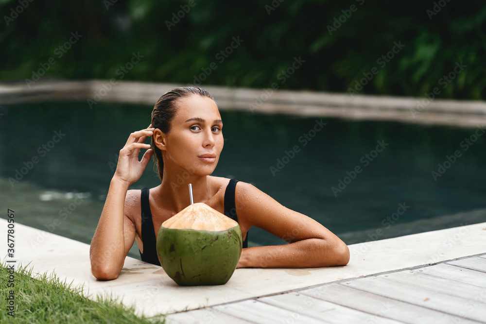 portrait of cute girl with coconut cocktail in the tropical pool. Horizontal. Outdoors lifestyle portrait of cute girl with coconut cocktail in the tropical pool. Horizontal. Outdoors lifestyle