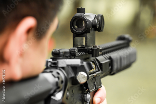 Military shooter with his precising assault rifle aiming and shooting target in the range