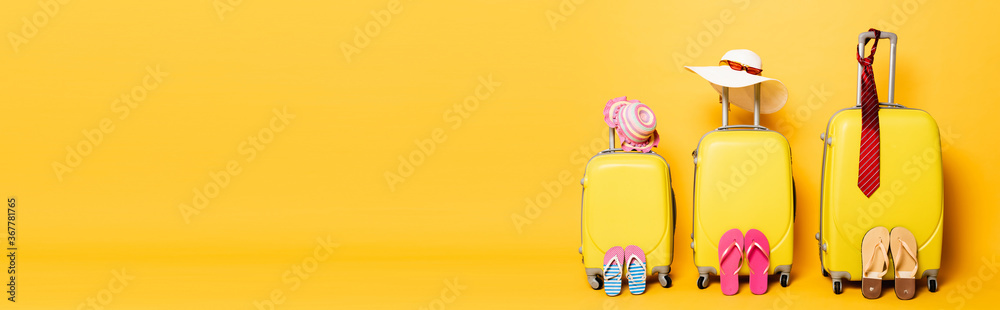 family travel bags with beach summer accessories isolated on yellow, panoramic shot - obrazy, fototapety, plakaty 