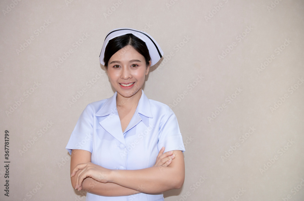 A gentle Asian young nurse in white clothing with arms folded isolated background. Portrait of smiley beautiful young nurse in white medical uniform holding hands crossed. Nurse or healthcare worker. A gentle Asian young nurse in white clothing with arms folded isolated background. Portrait of smiley beautiful young nurse in white medical uniform holding hands crossed. Nurse or healthcare worker.