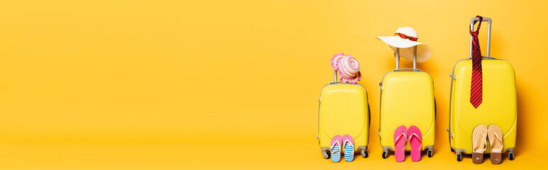 family travel bags with beach summer accessories isolated on yellow, panoramic shot