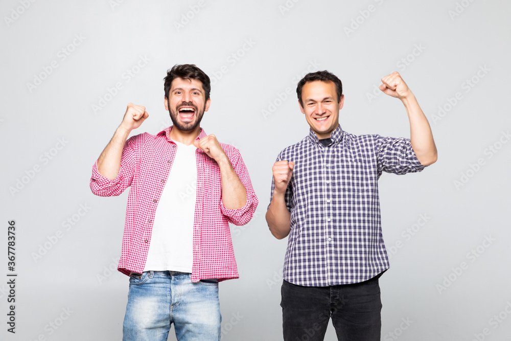 Obraz premium Portrait of a two joyful young men celebrating isolated over yellow background