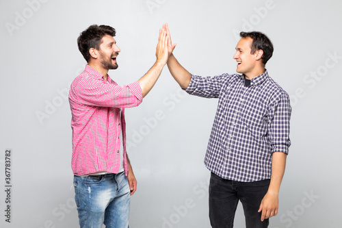 Portrait of two happy young men giving high five isolated over white background photo