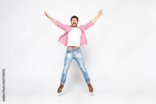 Excited young man jumping and smiling isolated on white background